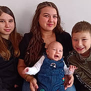 Imrán a rejoint le concours — aidez-le/la à gagner de superbes lots ! baby, child, smiling, portrait, couch, indoor, people, happy, casual_clothing, denim_overalls, sitting, group, family, young, long_hair, short_hair, neutral_background, light_skin, friendly, toddler