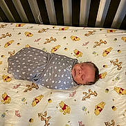 Le'Tavion is registered to the contest to win money with this photo: baby, swaddled, crib, blanket, sleeping, winnie_the_pooh, tigger, piglet, bed, sheet, pattern, gray, white, anchor, infant, child, cute, nursery, resting, soft