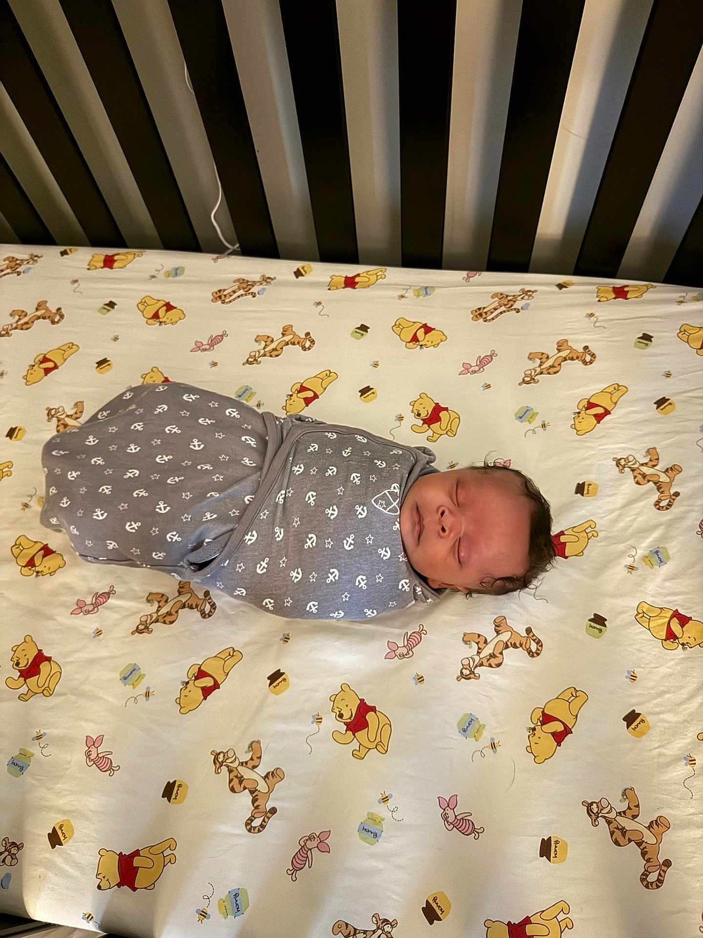 Le'Tavion is registered to the contest to win money with this photo: baby, swaddled, crib, blanket, sleeping, winnie_the_pooh, tigger, piglet, bed, sheet, pattern, gray, white, anchor, infant, child, cute, nursery, resting, soft