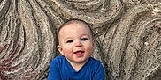 Zane is registered to the contest to win money with this photo: baby, child, smiling, blue_shirt, jeans, white_shoes, stone, carving, flower_pattern, outdoor, nature, portrait, cute, happy, playful, sitting, hands, face, head, daylight