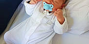 Kayden participe au concours pour gagner de l'argent avec cette photo : baby, newborn, pacifier, sleeping, white_onesie, bed, blanket, infant, clothing, cute, peaceful, hands, face, head, soft, indoors, resting, baby_accessory, fabric, toddler