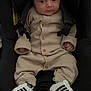 baby, infant, car_seat, clothing, sneakers, footwear, person, child, cute, indoor, seatbelt, stripes, small_hands, wide_eyes, knitted_outfit, buttoned, black, beige, portrait, seated