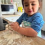 Dounia participe au concours pour gagner de l'argent avec cette photo : child, kitchen, flour, countertop, apron, blue_shirt, playing, cooking, young_child, face, hands, food_preparation, home, microwave, cabinet, smile, dirt, messy, indoor, person