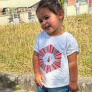 Dounia a rejoint le concours — aidez-le/la à gagner de superbes lots ! toddler, child, smiling, outdoor, grass, white_tshirt, denim_shorts, sunlight, fence, building, happy, cute, portrait, standing, casual_clothing, shorts, daylight, nature, playful, young_child