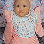 baby, infant, child, peach_clothing, headband, bib, floral_pattern, butterfly_pattern, blanket, soft_texture, pout, wide_eyes, sitting, indoor, cute, chubby_cheeks, portrait, baby_fashion, pink, adorable