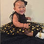 Janiyah joined the competition — help win amazing prizes! baby, child, smiling, dress, black_dress, gold_polka_dots, headband, bow, sitting, blanket, shoes, happy, cute, indoor, portrait, infant, fashion, toddler, person, clothing
