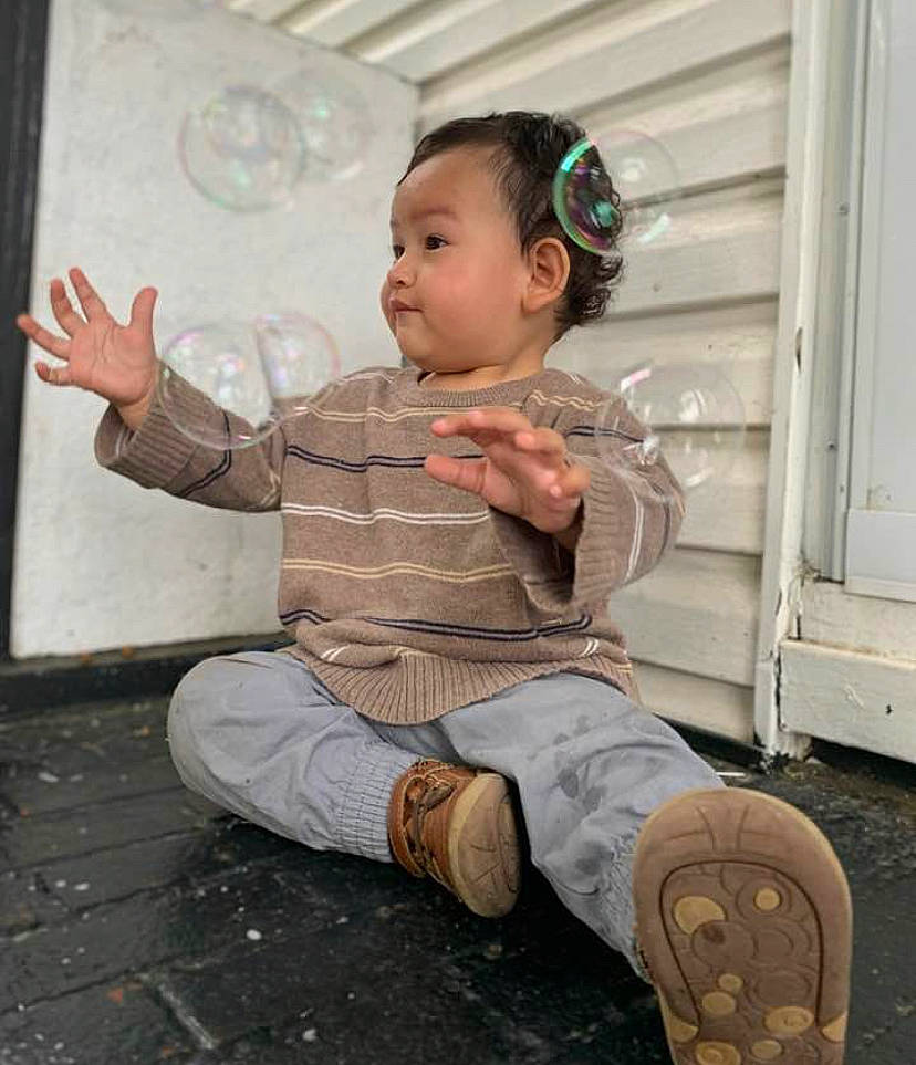 Issac is registered to the contest to win money with this photo: baby_toddler_clothing, child, flooring, foot, fun, grass, happy, head, human_leg, joint, leisure, person, play, sandal, sitting, sleeve, sock, standing, toddler, wood