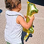 Orlando is registered to the contest to win money with this photo: back_view, balloon, casual_clothing, celebration, child, curly_hair, daytime, number_one, outdoor, party, pavement, shadow, shorts, sleeveless_shirt, socks, standing, sunlight, toddler, toy, young_child