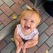 Eva a rejoint le concours — aidez-le/la à gagner de superbes lots ! baby, barefoot, blond, bricks, casual_clothing, child, cute, daylight, expression, hair, happy, infant, leaves, looking_up, outdoor, pavement, playful, portrait, sitting, smile