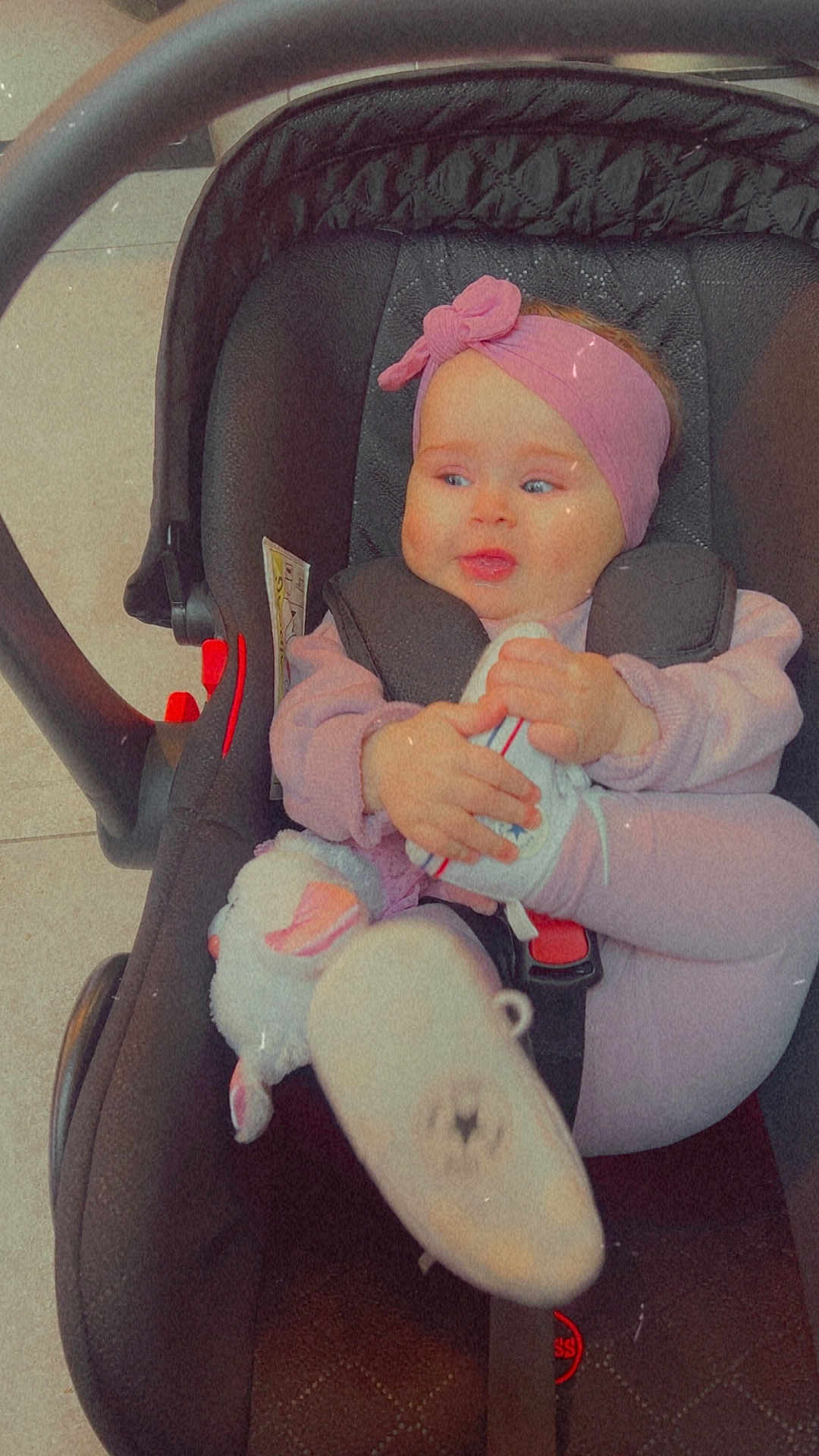 Luna participe au concours pour gagner de l'argent avec cette photo : baby, infant, car_seat, pink_headband, stuffed_animal, clothing, footwear, child, cute, indoor, seat_belt, toy, smiling, person, portrait, headwear, holding, toddler, seat, young_child