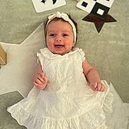 Olympe a rejoint le concours — aidez-le/la à gagner de superbes lots ! baby, infant, smiling, white_dress, headband, lying_down, carpet, star_pattern, play_cards, soft_toys, happy, cute, child, indoors, portrait, young_child, clothing, baby_girl, floor, decor