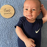 Hunter is registered to the contest to win money with this photo: arm, baby, blue_blanket, cute, expression, face, hand, indoor, infant, lying_down, milestone, navy_blue, newborn, nike_logo, onesie, portrait, skin, soft_texture, two_months, wooden_plaque