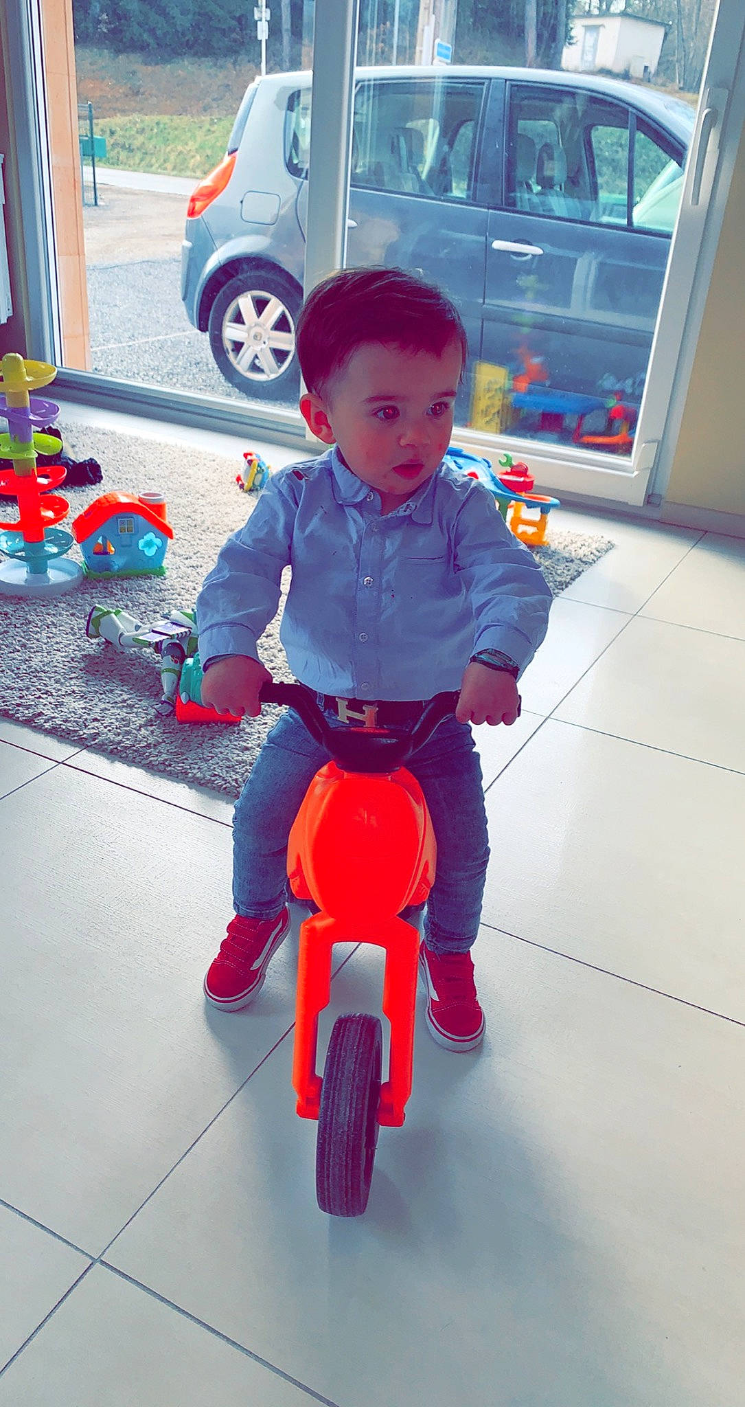 Archie participe au concours pour gagner de l'argent avec cette photo : baby_toddler_clothing, car, carmine, child, cleanliness, electric_blue, floor, flooring, fun, leg, person, recreation, red, shoe, sitting, sneakers, tire, toddler, vehicle, vehicle_door
