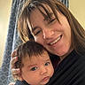 woman, baby, smile, face, portrait, indoor, curtain, baby_carrier, holding, person, head, hair, clothing, skin, closeup, parent, child, happy, family, love