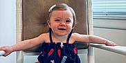 Wren joined the competition — help win amazing prizes! baby, child, smiling, rocking_chair, cushion, dress, hair_clip, indoor, window_blinds, arms_outstretched, footwear, happy, person, infant, seat, furniture, light, portrait, young_child, comfortable
