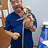 Margarita Olive joined the competition — help win amazing prizes! accessory, animal, blue_scrubs, clothing, dog, door, hand, happy, hat, holding, indoor, man, medical_office, person, pet, poster, small_dog, smile, tongue_out, watch