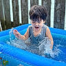 child, toddler, pool, swimming, water, splashing, outdoor, summer, portrait, smiling, happy, wet, sleeveless_shirt, dark_hair, closed_eyes, inflatable_pool, crocodile, playtime, water_drops, backyard