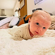 Léonie participe au concours pour gagner de l'argent avec cette photo : baby, infant, newborn, tummy_time, blanket, bed, soft_texture, blue_eyes, face, cheeks, onesie, lying_down, portrait, indoor, home_interior, pillow, curious_expression, close_up, adorable, nursery
