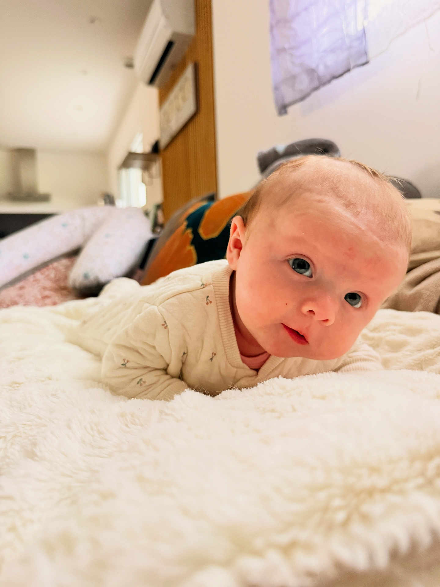 Léonie a rejoint le concours — aidez-le/la à gagner de superbes lots ! baby, infant, newborn, tummy_time, blanket, bed, soft_texture, blue_eyes, face, cheeks, onesie, lying_down, portrait, indoor, home_interior, pillow, curious_expression, close_up, adorable, nursery