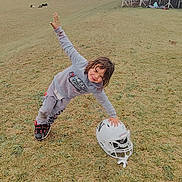 James joined the competition — help win amazing prizes! child, grass, football_helmet, sports, bleachers, field, outdoor, playful, gray_clothing, sneakers, person, smiling, happy, daytime, casual, fun, young, leisure, team_sport, nature