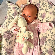 Miller Grace joined the competition — help win amazing prizes! baby, blanket, bunny, carpet, child, cozy, cute, flooring, floral_pattern, head, indoor, infant, laying_down, person, pink_clothing, plush_toy, portrait, smiling, soft_toy, young_child