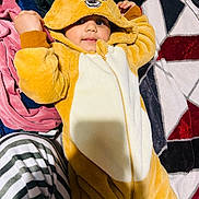 Sartaj is registered to the contest to win money with this photo: baby, blanket, child, clothing, colorful, costume, cozy, cute, deer, face, hand, hood, indoors, lying_down, onesie, playful, plush, smile, soft_texture, striped_pants