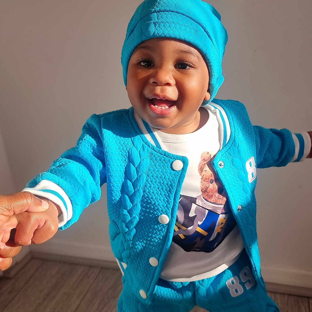 Sioni joined the competition — help win amazing prizes! baby, bodypart, cap, clothing, face, finger, footwear, hand, happy, hat, head, knitwear, pants, person, photography, portrait, shoe, smile, sweater, wood