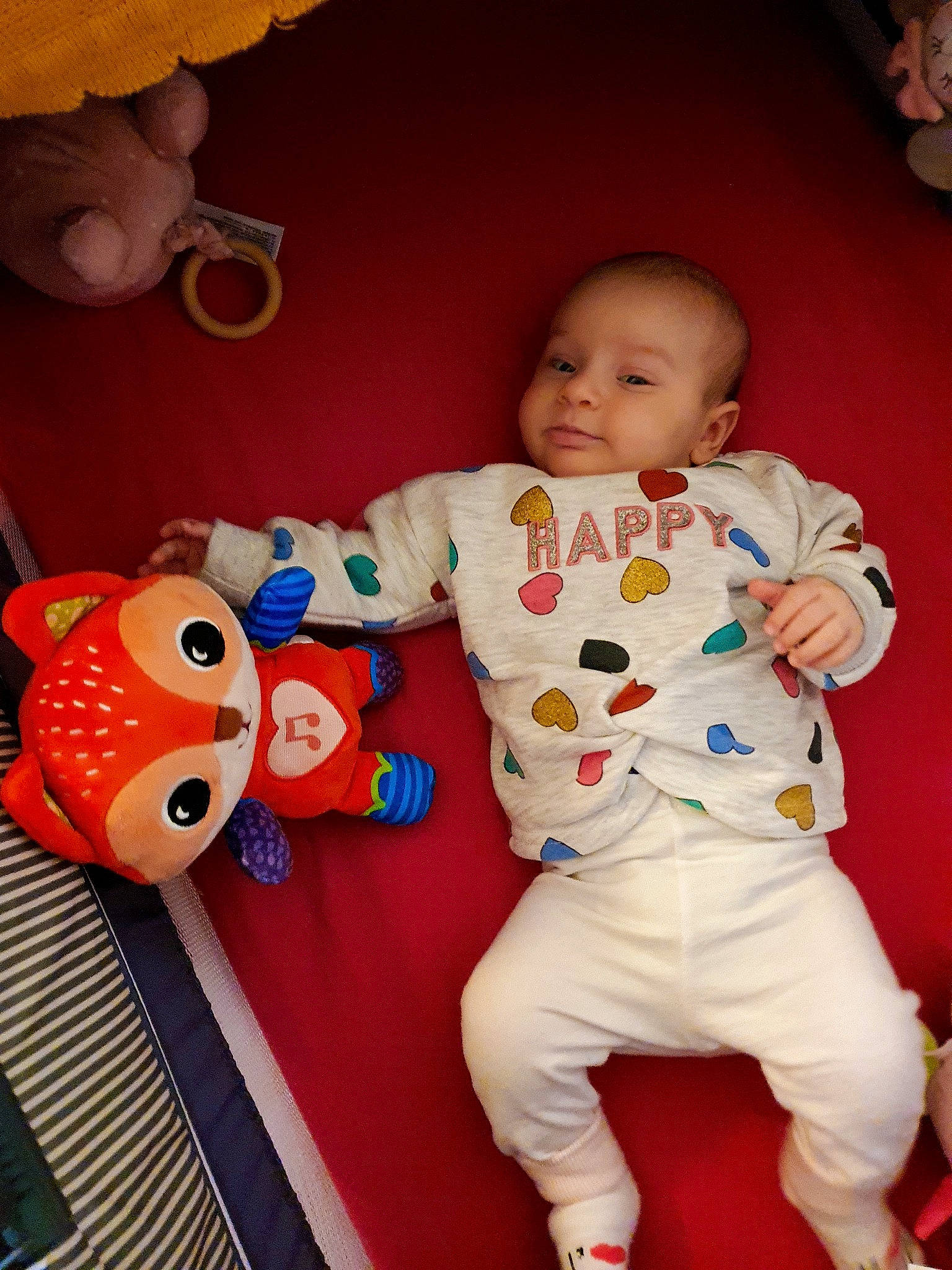 Céline participe au concours pour gagner de l&#x27;argent avec cette photo : arm, baby, baby_toddler_clothing, cheek, facial_expression, finger, fun, happy, mammal, orange, organ, person, pink, product, red, skin, sleeve, smile, textile, toy