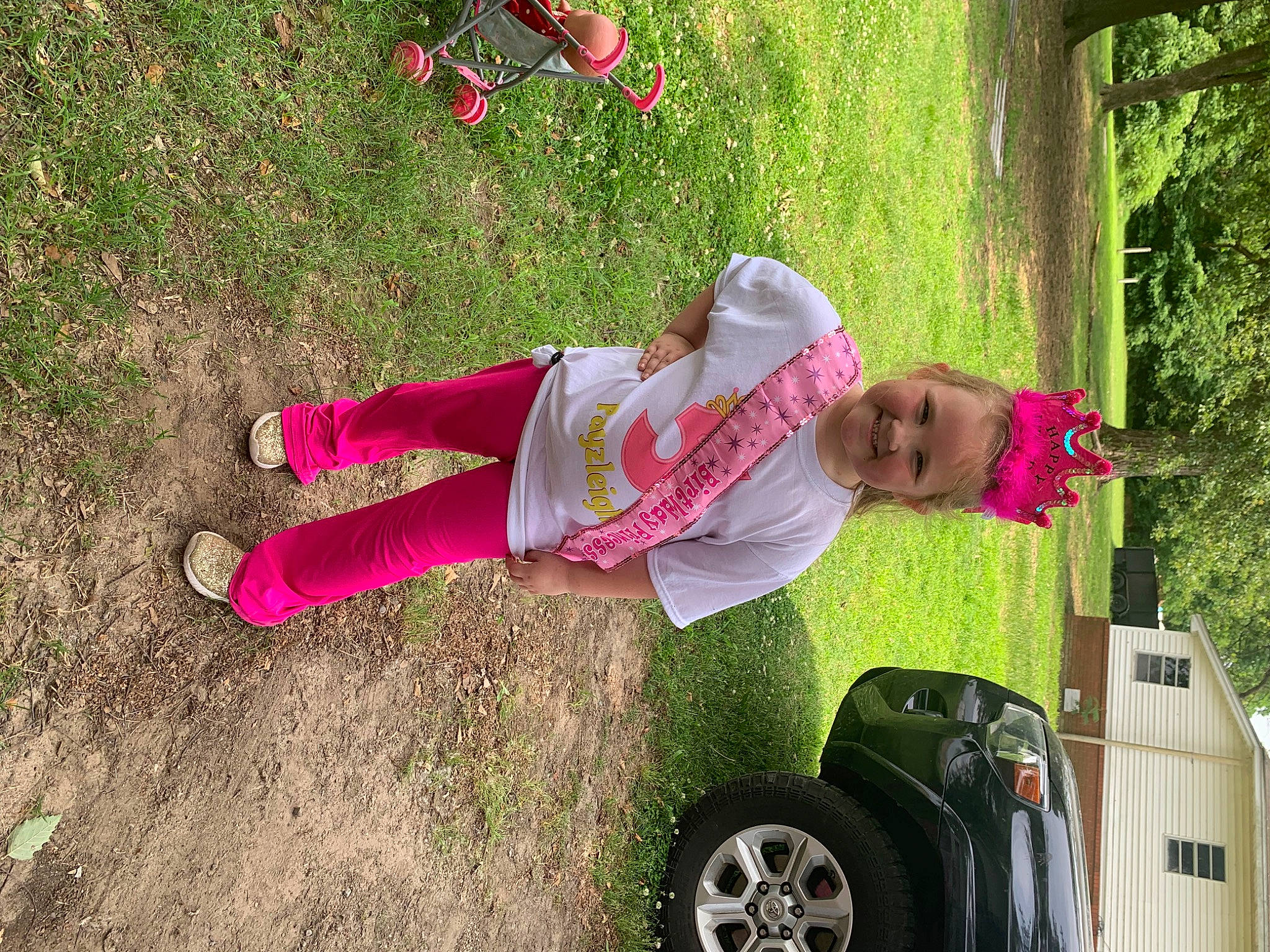 Payzleigh is registered to the contest to win money with this photo: automotive_exterior, automotive_tire, car, fender, fun, grass, joy, leisure, motor_vehicle, people_in_nature, person, photograph, pink, plant, smile, sneakers, tire, tread, tree, vehicle