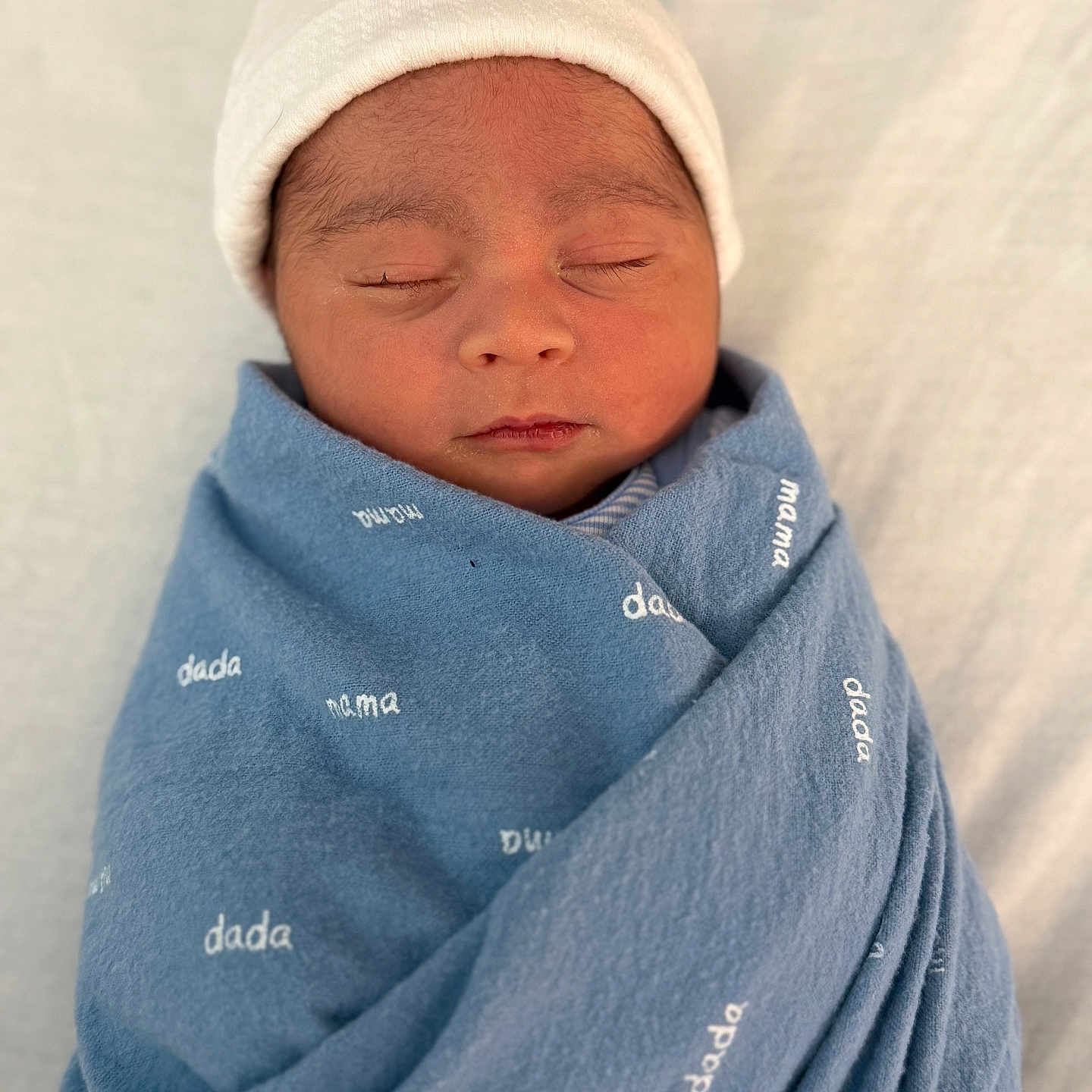 Liam joined the competition — help win amazing prizes! baby, beanie, blanket, bonnet, cap, clothing, coat, face, hat, head, hood, newborn, person, photography, portrait, sleeping, towel