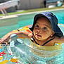 child, toddler, inflatable_ring, pool, water, sun_hat, summer, outdoor, swimming, float, baby, sunlight, vacation, recreation, fun, playful, skin, face, cute, leisure