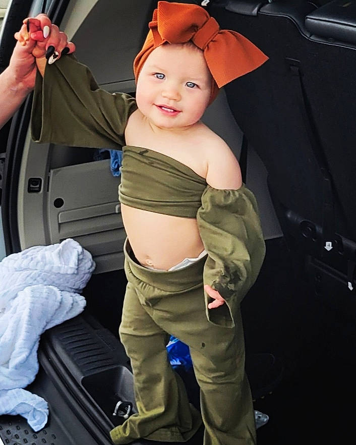 Harper is registered to the contest to win money with this photo: abdomen, baby_carriage, bag, belt, chest, fun, gesture, hairstyle, hand, headwear, joint, muscle, person, shoulder, smile, standing, textile, thumb, toddler, trunk