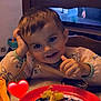 Lorenzo a rejoint le concours — aidez-le/la à gagner de superbes lots ! child, toddler, smile, face, plate, food, table, chair, indoor, television, furniture, hand, clothing, heart_emoji, meal, dining, hair, expression, sitting, cute
