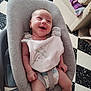 Armand participe au concours pour gagner de l'argent avec cette photo : baby, smiling, infant, baby_seat, bib, plush_toy, strap, diaper, indoor, floor, checkered_floor, couch, blanket, happy, person, child, seat, clothing, cute, home