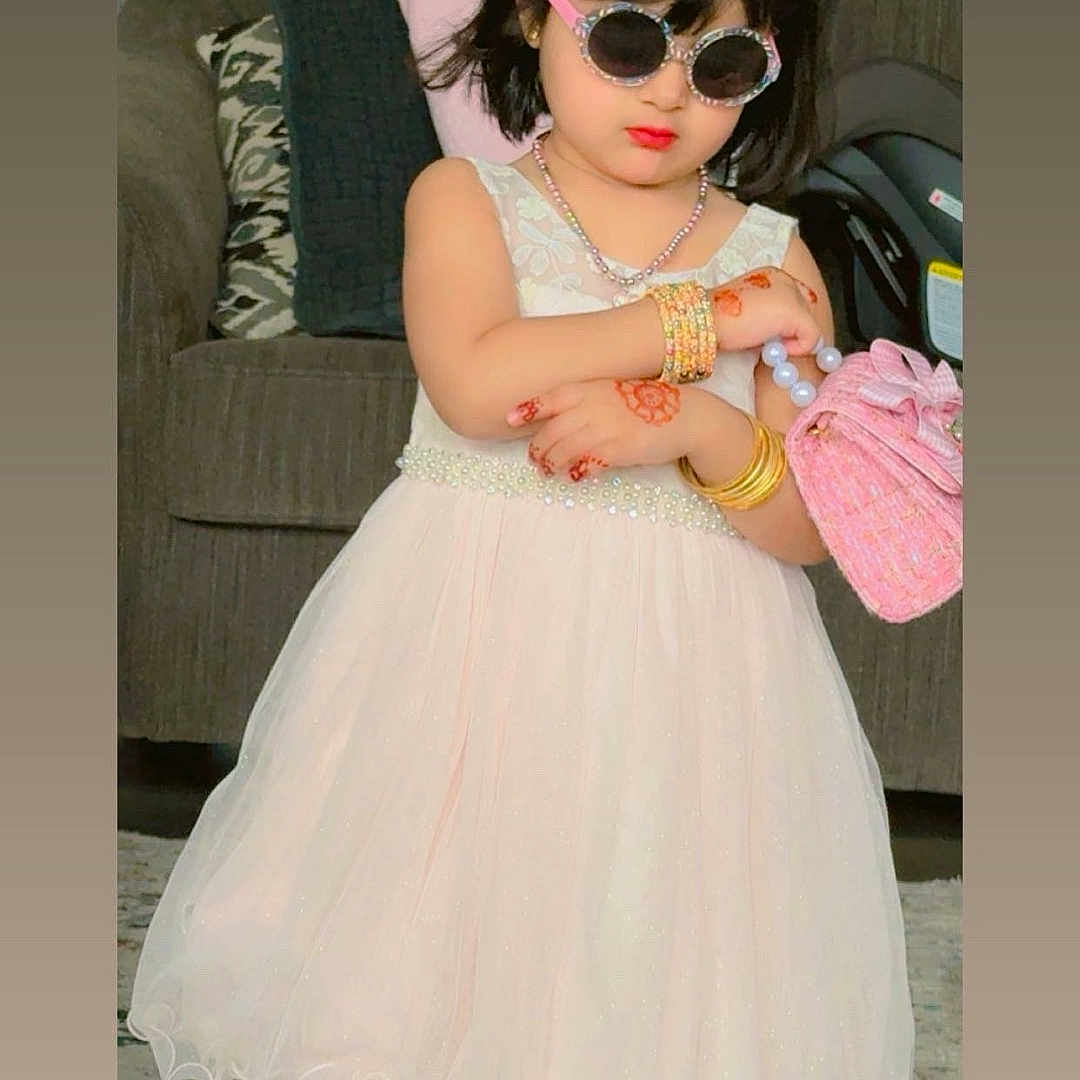 Zahra is registered to the contest to win money with this photo: child, girl, dress, sunglasses, tiara, purse, bracelets, necklace, indoor, carpet, sofa, cushions, fashion, accessories, portrait, cute, confident, home, person, toddler