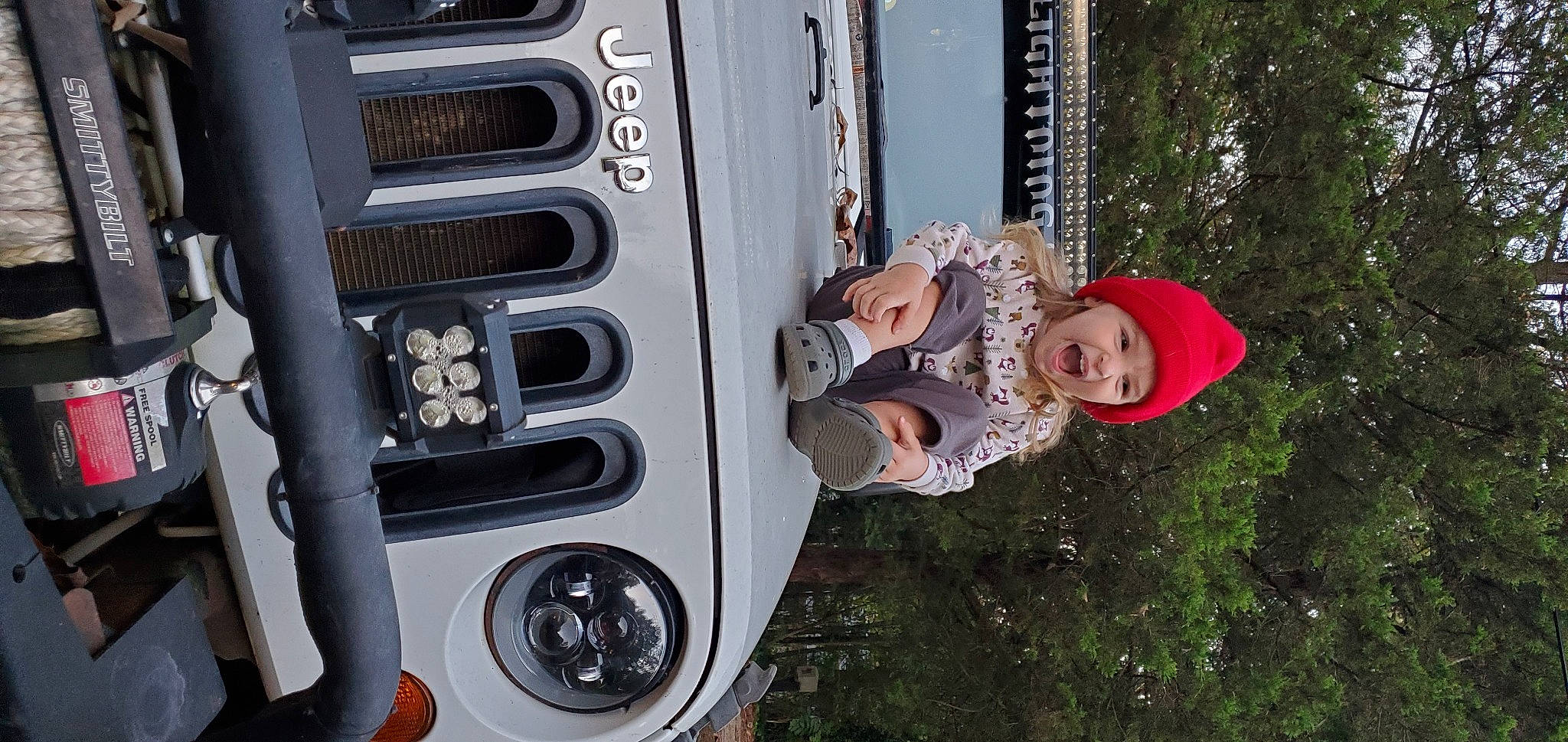 Raven is registered to the contest to win money with this photo: auto_part, automotive_design, automotive_exterior, automotive_lighting, automotive_tire, automotive_wheel_system, bumper, fender, hat, headwear, hood, hubcap, machine, motor_vehicle, person, smile, sun_hat, tire, tree, vehicle