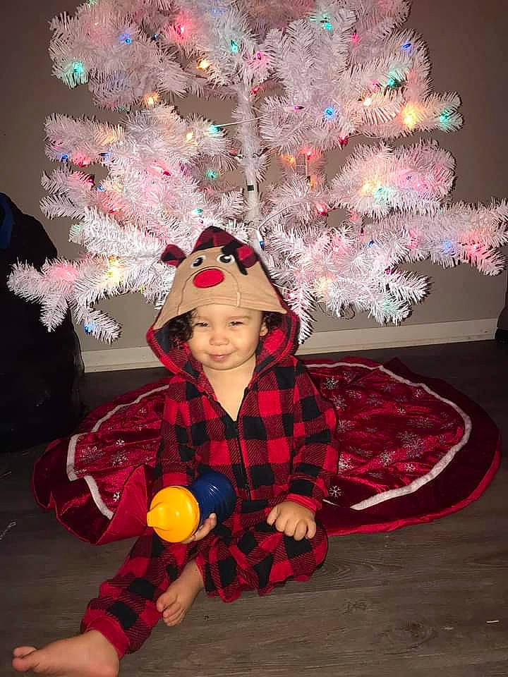 Ta'Vion is registered to the contest to win money with this photo: baby_toddler_clothing, child_model, christmas, christmas_decoration, christmas_tree, costume, costume_accessory, costume_hat, festival, headgear, headwear, holiday, human, interior_design, joy, ornament, overall, party_supply, person, play