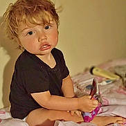 Talon joined the competition — help win amazing prizes! toddler, child, bed, blanket, snack, indoor, curly_hair, black_shirt, sitting, young, person, pink, pattern, toy, cute, face, holding, relaxed, young_child, home