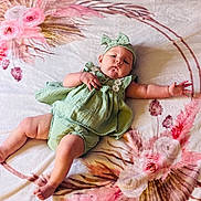 Willow is registered to the contest to win money with this photo: baby, infant, child, green_outfit, headband, blanket, floral_pattern, lying_down, cute, chubby_legs, pouty_face, reaching_hand, soft_texture, indoors, comfortable, relaxed, skin, expression, adorable, young