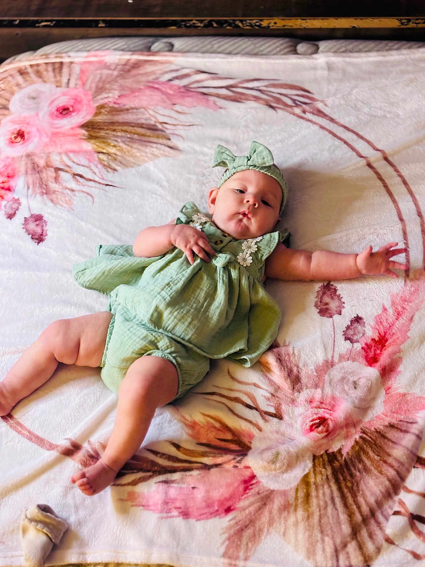 Willow is registered to the contest to win money with this photo: baby, infant, child, green_outfit, headband, blanket, floral_pattern, lying_down, cute, chubby_legs, pouty_face, reaching_hand, soft_texture, indoors, comfortable, relaxed, skin, expression, adorable, young