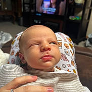 Taylor joined the competition — help win amazing prizes! baby, newborn, infant, blanket, hand, ring, person, face, sleepy, indoor, television, background, clothing, pattern, lap, skin, expression, cozy, resting, comfort