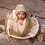 adorable, baby, basket, blanket, brown_skin, cozy, cute, decorative, expression, headwear, indoors, infant, knit_hat, lace, newborn, portrait, pout, soft_texture, wooden_beads, wrapped