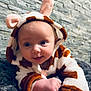 baby, blanket, child, cozy, crawling, cute, expression, face, giraffe_costume, headwear, hoodie, indoors, infant, person, plush, smiling, soft_texture, stone, wall, warm_clothing