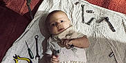 Emmylou is registered to the contest to win money with this photo: baby, carpet, curious, dirty_clothes, equipment, face, hands, indoor, infant, lying_down, mechanic, metal, motorcycle, playful, pliers, red, screwdriver, tools, white_cloth, wrench