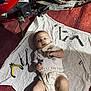 baby, carpet, curious, dirty_clothes, equipment, face, hands, indoor, infant, lying_down, mechanic, metal, motorcycle, playful, pliers, red, screwdriver, tools, white_cloth, wrench