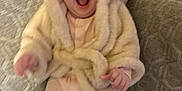 Emmylou joined the competition — help win amazing prizes! baby, child, infant, smiling, laughing, coat, jacket, fur, couch, furniture, indoors, happy, person, seated, clothing, warm, cute, cozy, expression, home