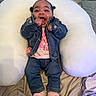 baby, denim_jacket, jeans, pink_slippers, unicorn_slippers, cushion, blanket, pillow, smiling, happy, indoor, child, cute, clothing, footwear, person, infant, lying_down, cozy, soft
