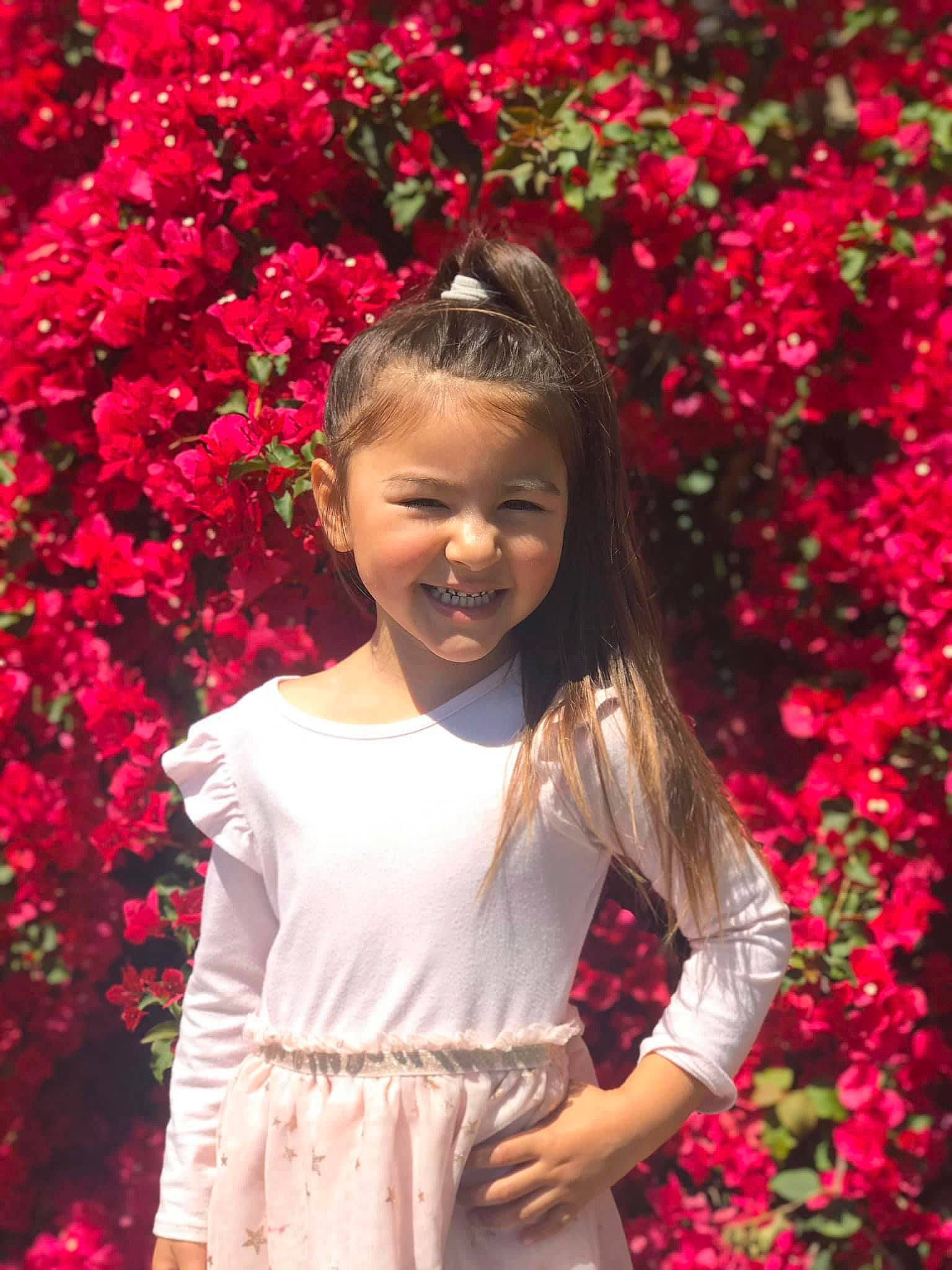 Rubi is registered to the contest to win money with this photo: blossom, botany, bougainvillea, child, child_model, floral_design, flower, happy, joy, long_hair, perennial_plant, person, petal, photography, pink, plant, red, shrub, smile, spring