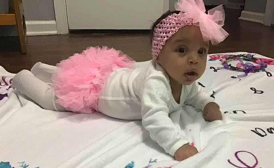 Wylie is registered to the contest to win money with this photo: baby, baby_toddler_clothing, cap, cheek, child, comfort, costume_hat, event, fashion_accessory, fun, hair_accessory, happy, headgear, headwear, linens, magenta, person, pink, room, skin