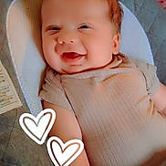 Olover is registered to the contest to win money with this photo: baby, smiling, infant, cushion, baby_seat, clothing, happy, cute, child, indoor, person, seatbelt, fabric, heart_doodle, arm, head, face, skin, comfort, relaxed